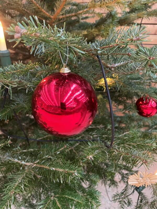 Rote Christbaumkugeln schmücken die Weihnachtsbäume in der Gemeindehalle